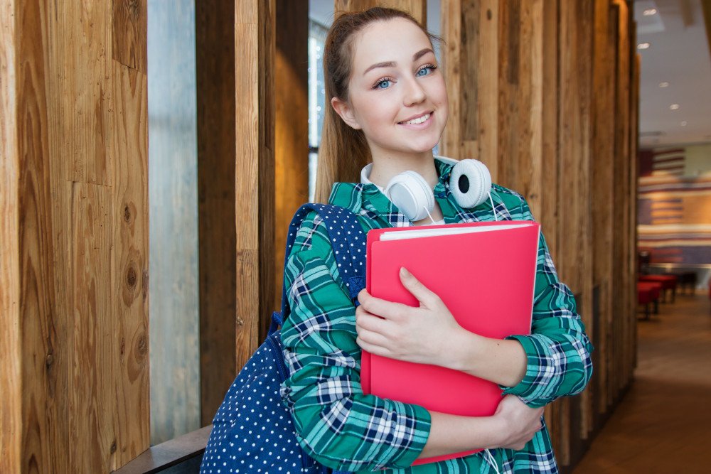 female student smiling with folder in her arms