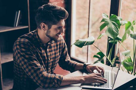 A man smiling while working on his laptop